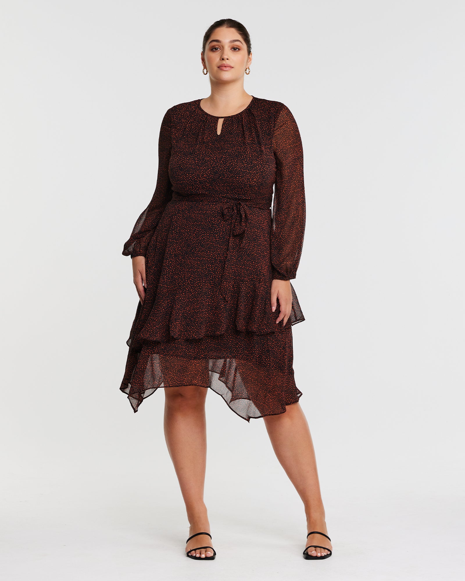 The model is wearing a Camilla Dot Dress with a handkerchief hemline and long sleeves.