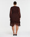 A woman wearing the Camilla Dot Dress, a long sleeved brown dress with an asymmetrical tier.