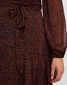 A woman wearing the Camilla Dot Dress, a long-sleeved, asymmetrical-tiered dress.