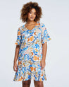 A plus size woman wearing an Estelle Gazania Dress in a blue and orange floral print.