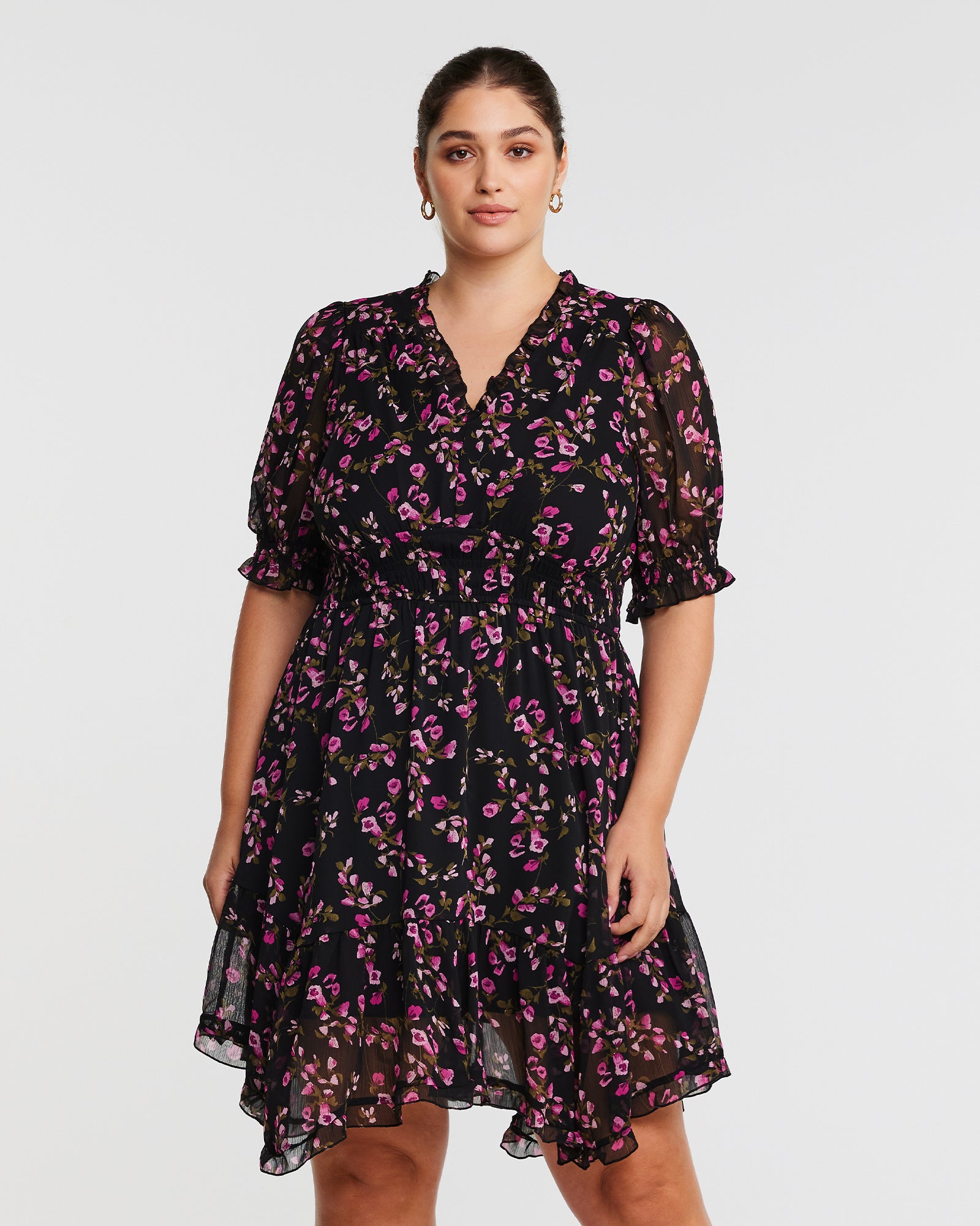 A plus size woman wearing a Tulip Garden Shirred Floral Mini Dress with maintenance instructions.