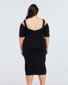 The back view of a woman wearing an Estelle black cold shoulder midi Sacha Dress.