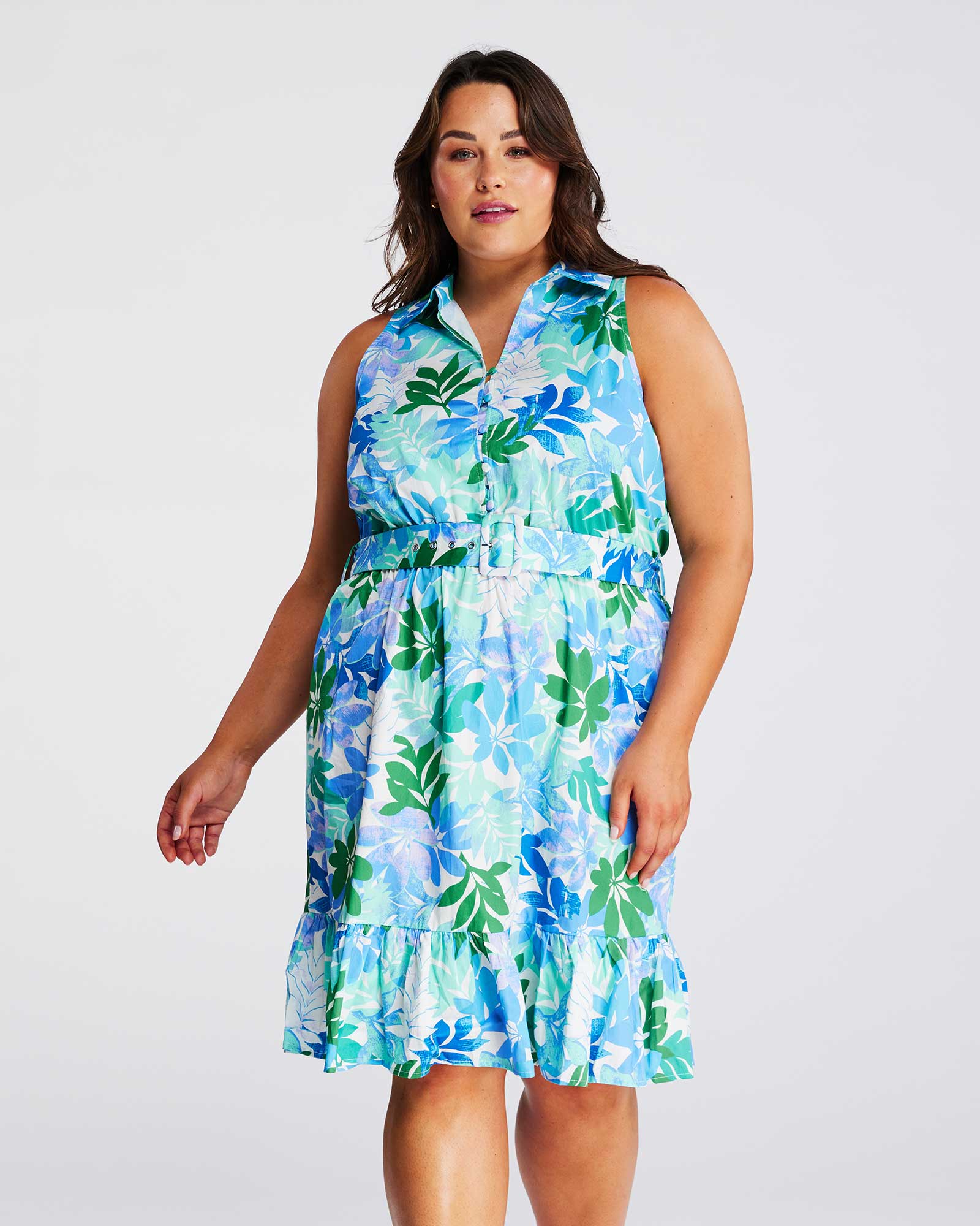 A woman wearing the Estelle Travola Dress, a blue and green floral print dress.