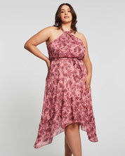 A plus size woman wearing a Estelle Sophia Halter Dress in a pink floral print.