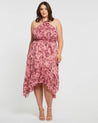 A plus size woman wearing an Estelle Sophia Halter Dress in pink floral.