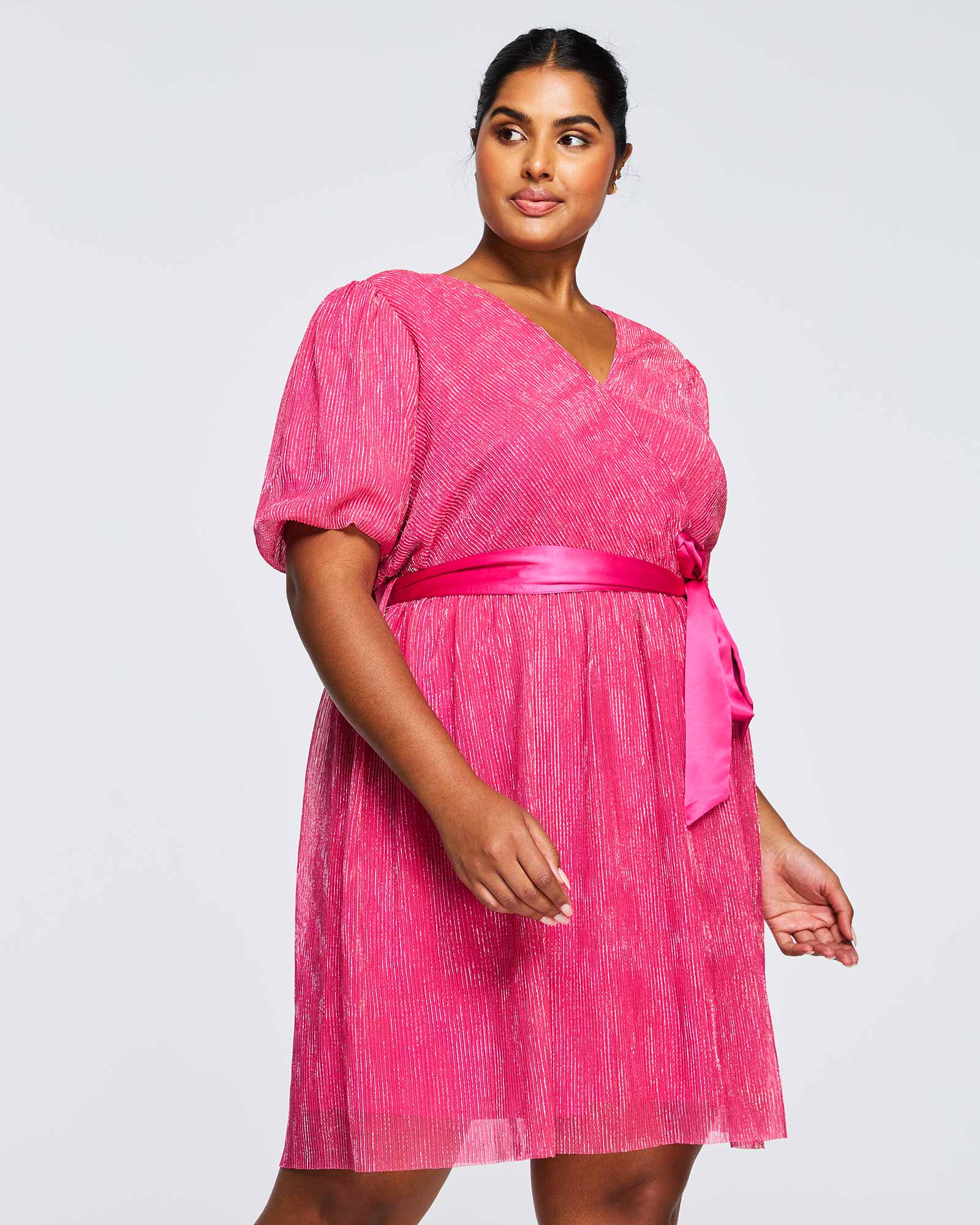 A plus size woman wearing an Estelle Avalone Dress with a pink belt.