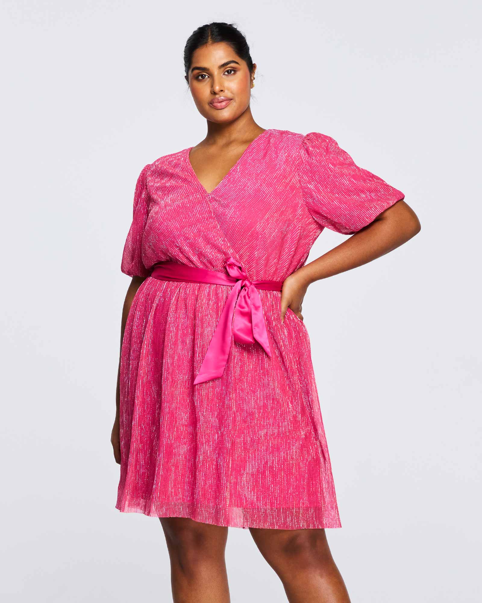 A plus size woman is posing in an Estelle Avalone Dress.