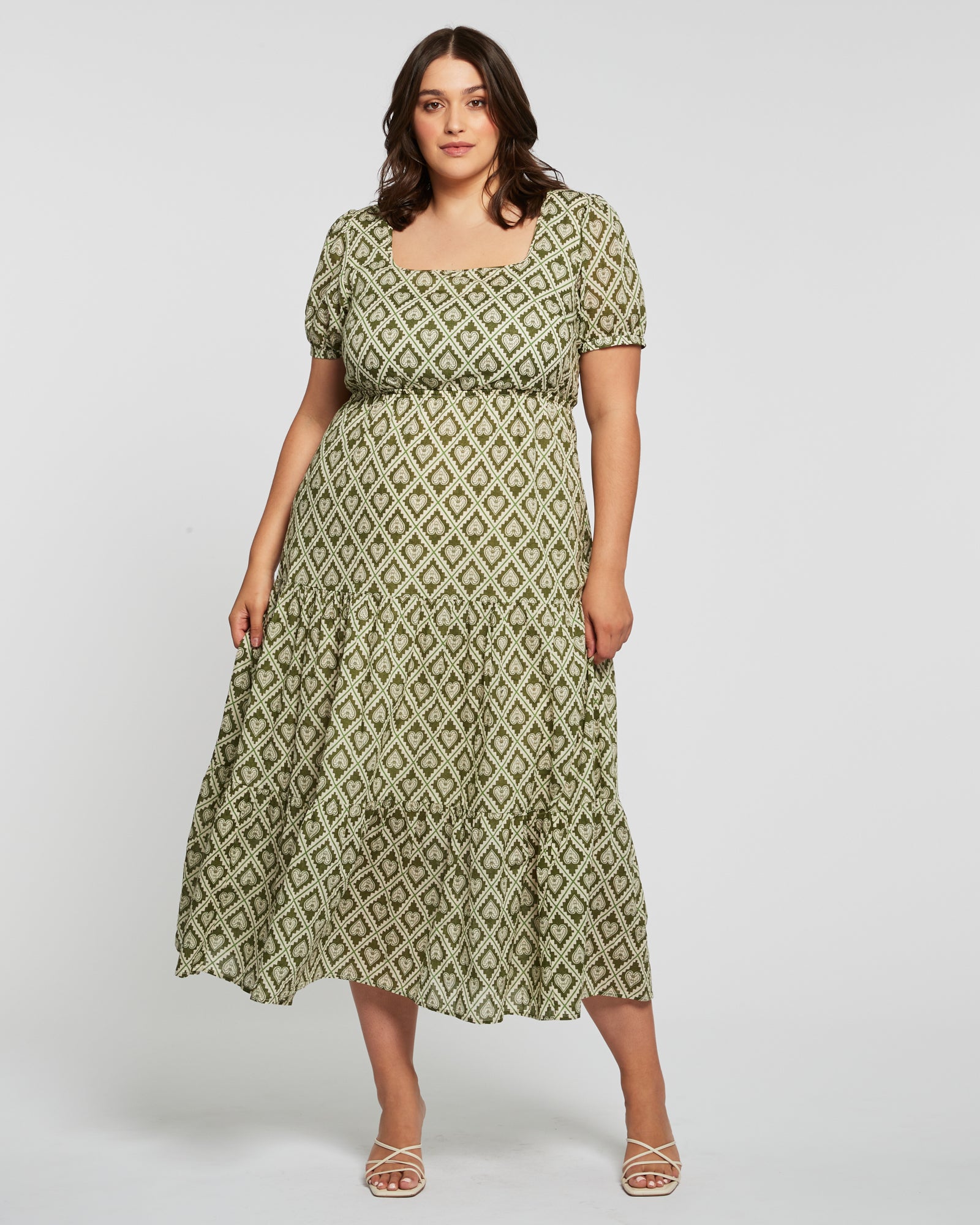 The plus size woman is wearing an Estelle Olive Heart Maxi Dress.