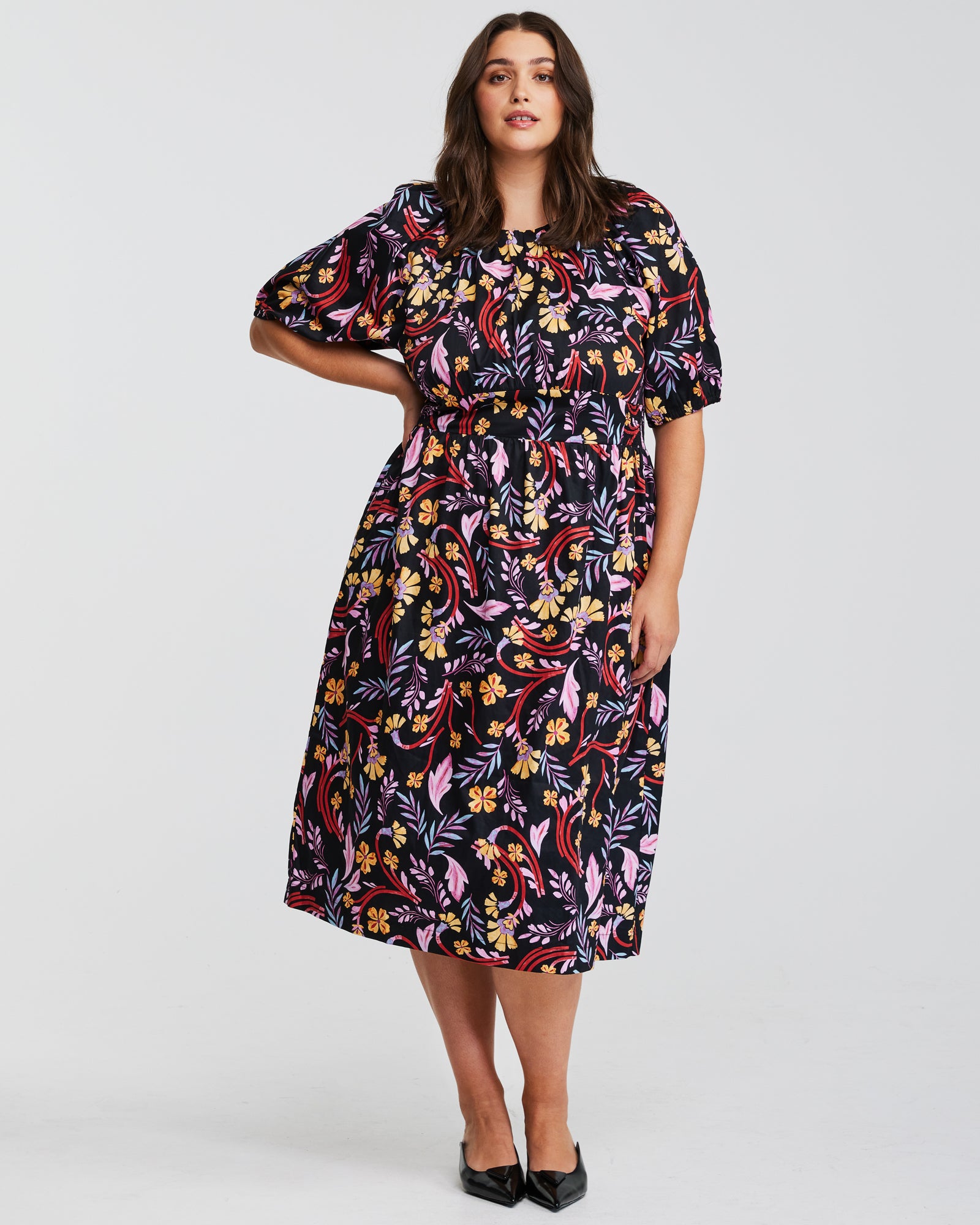 A plus size woman wearing the Estelle Flamingo Floral Midi Puff Sleeve Dress.