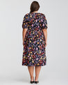 The back view of a plus size woman wearing the Estelle Flamingo Floral Midi Puff Sleeve Dress.