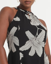 Black sleeveless top with white floral pattern worn by a model on a light gray background