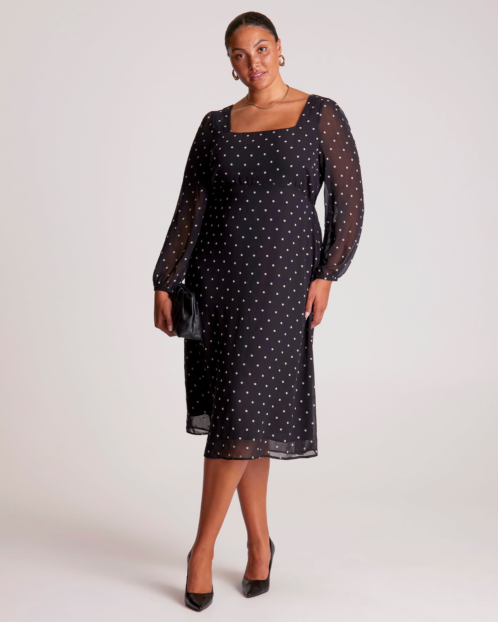 Woman wearing a black dress with sheer sleeves on a white background