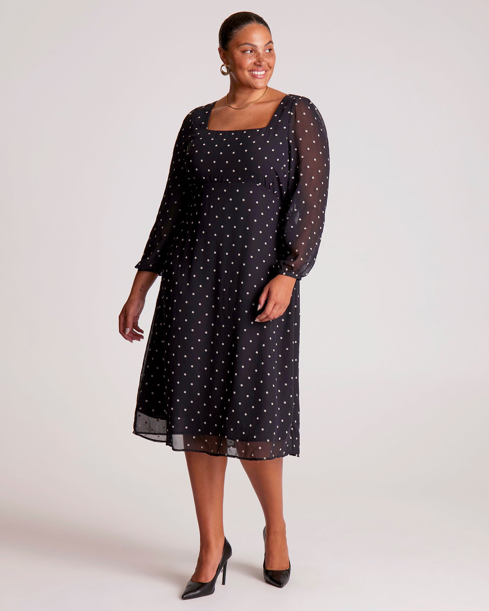 Woman wearing a black dress with white polka dots on a white background