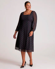 Woman wearing a black dress with white polka dots on a white background