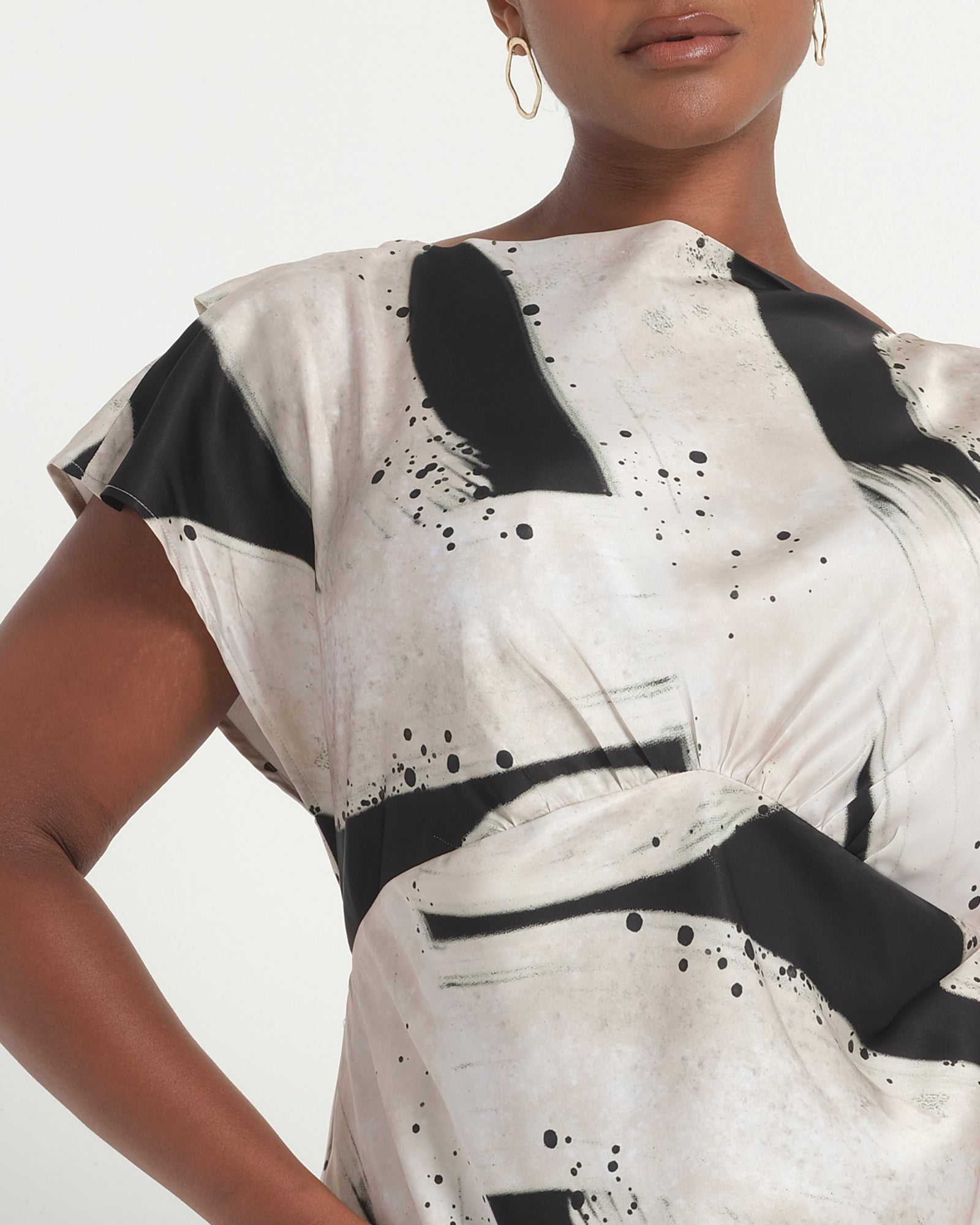 Woman wearing a black and white abstract patterned dress on a light gray background