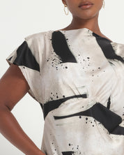 Woman wearing a black and white abstract patterned dress on a light gray background