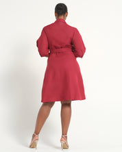 A woman viewed from the back wearing a red belted wrap dress with long sleeves, paired with beige high-heeled sandals, against a plain white studio background.