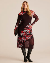 Woman wearing a floral dress with black boots on a beige background
