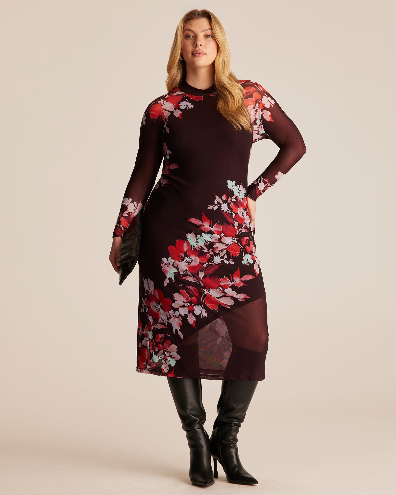 Woman wearing a floral dress with black boots on a beige background