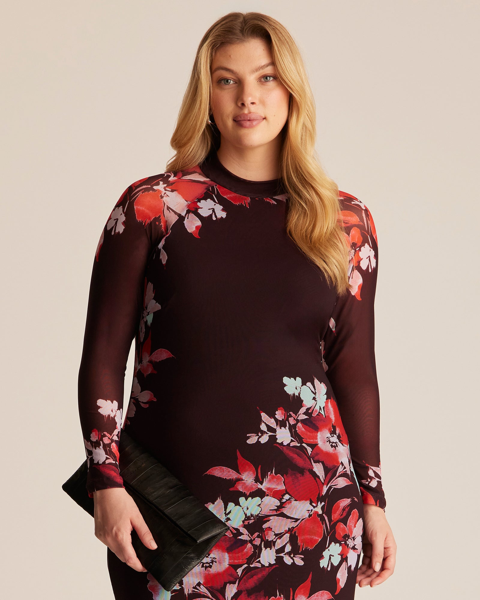 Woman wearing a dark red dress with floral patterns on a beige background
