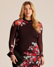 Woman wearing a dark red dress with floral patterns on a beige background