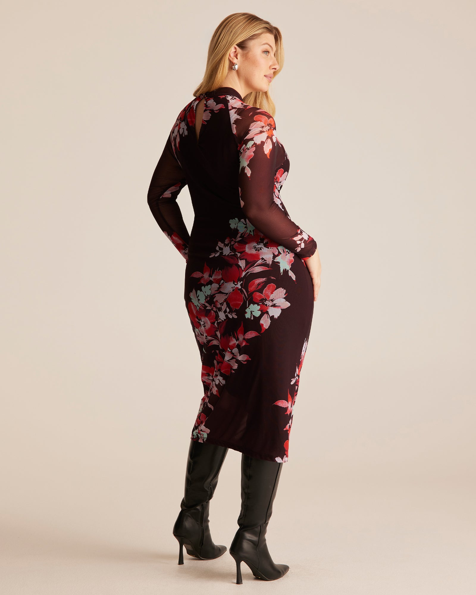 Woman wearing a black floral dress on a beige background