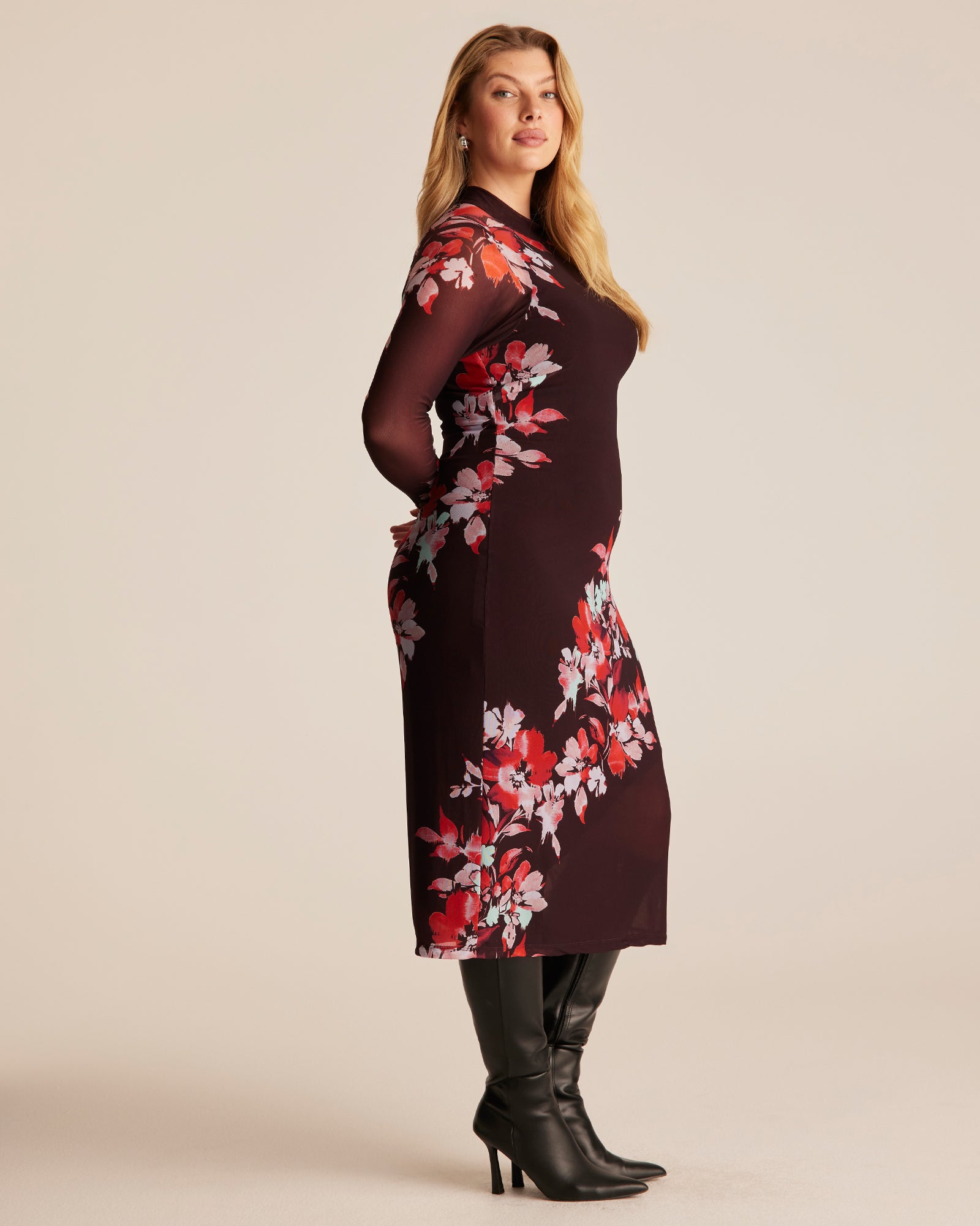 Woman wearing a dark dress with red floral pattern on a beige background