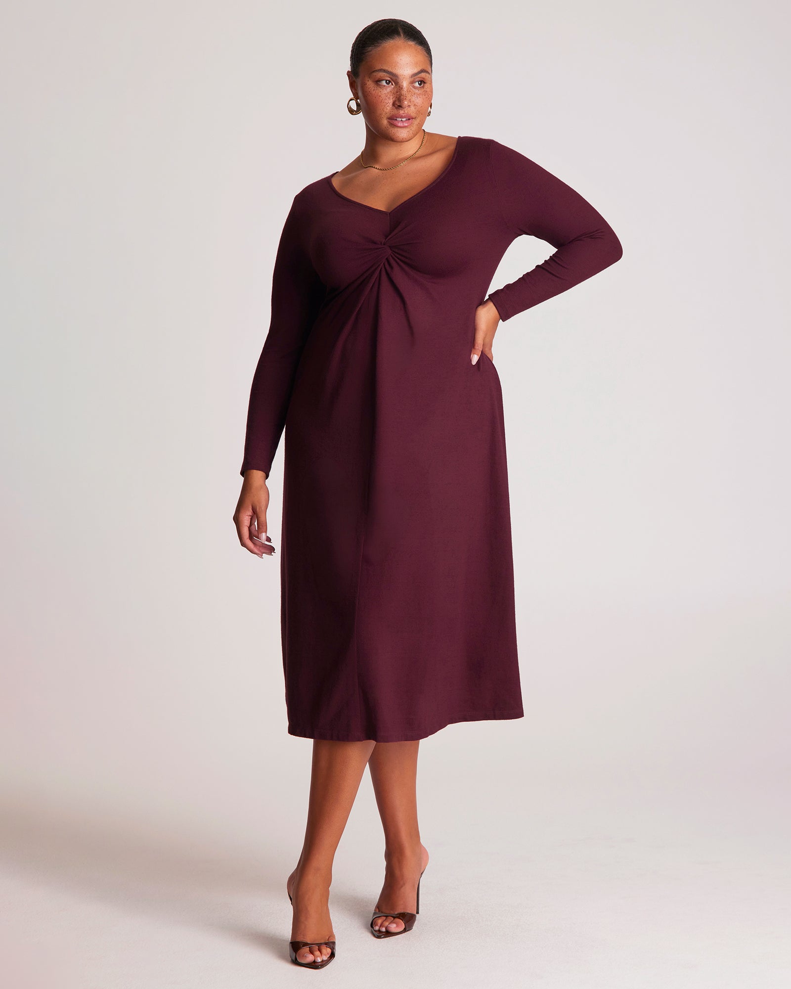Woman wearing a burgundy dress with long sleeves on a white background