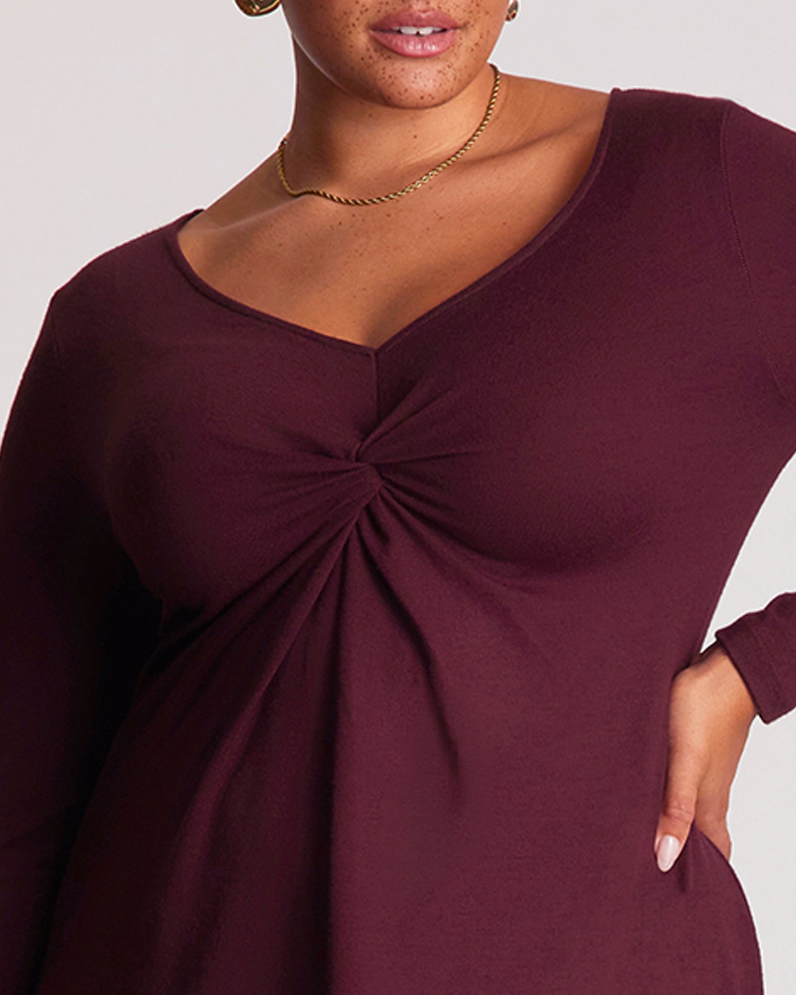 Maroon dress with a knot detail on a plain background