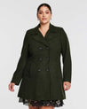 A plus size woman wearing a fully functioning double-breasted olive Homeland coat and floral dress.