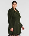 A plus size woman wearing an olive double-breasted Homeland Coat with fully functioning pockets.