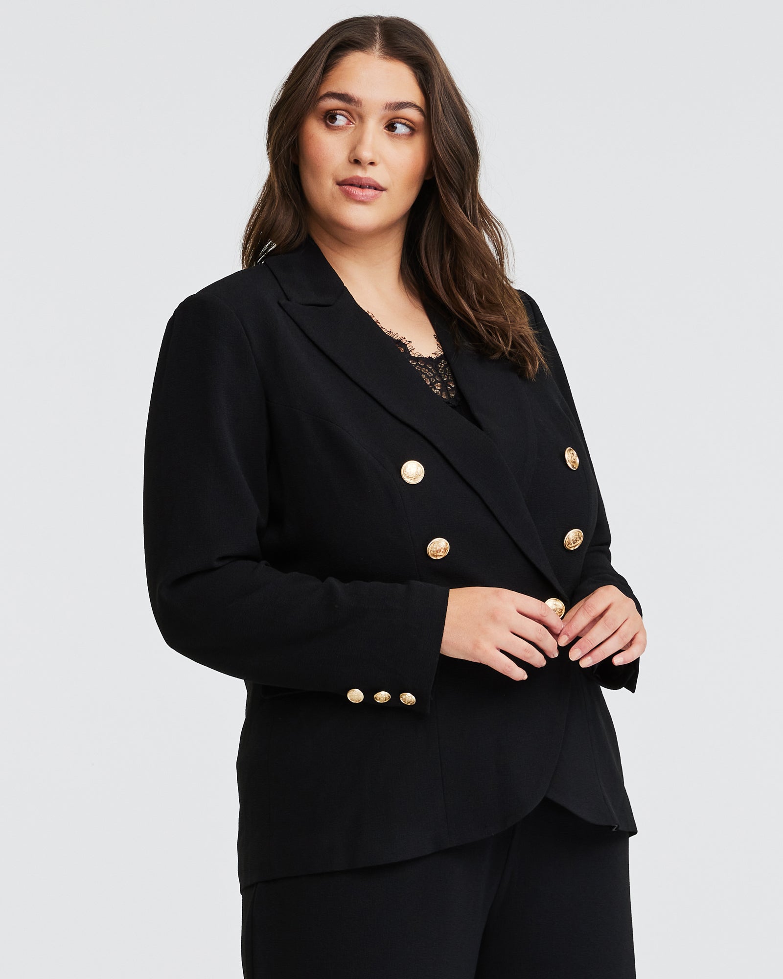 A woman wearing a Estelle Clever Jacket with gold buttons.