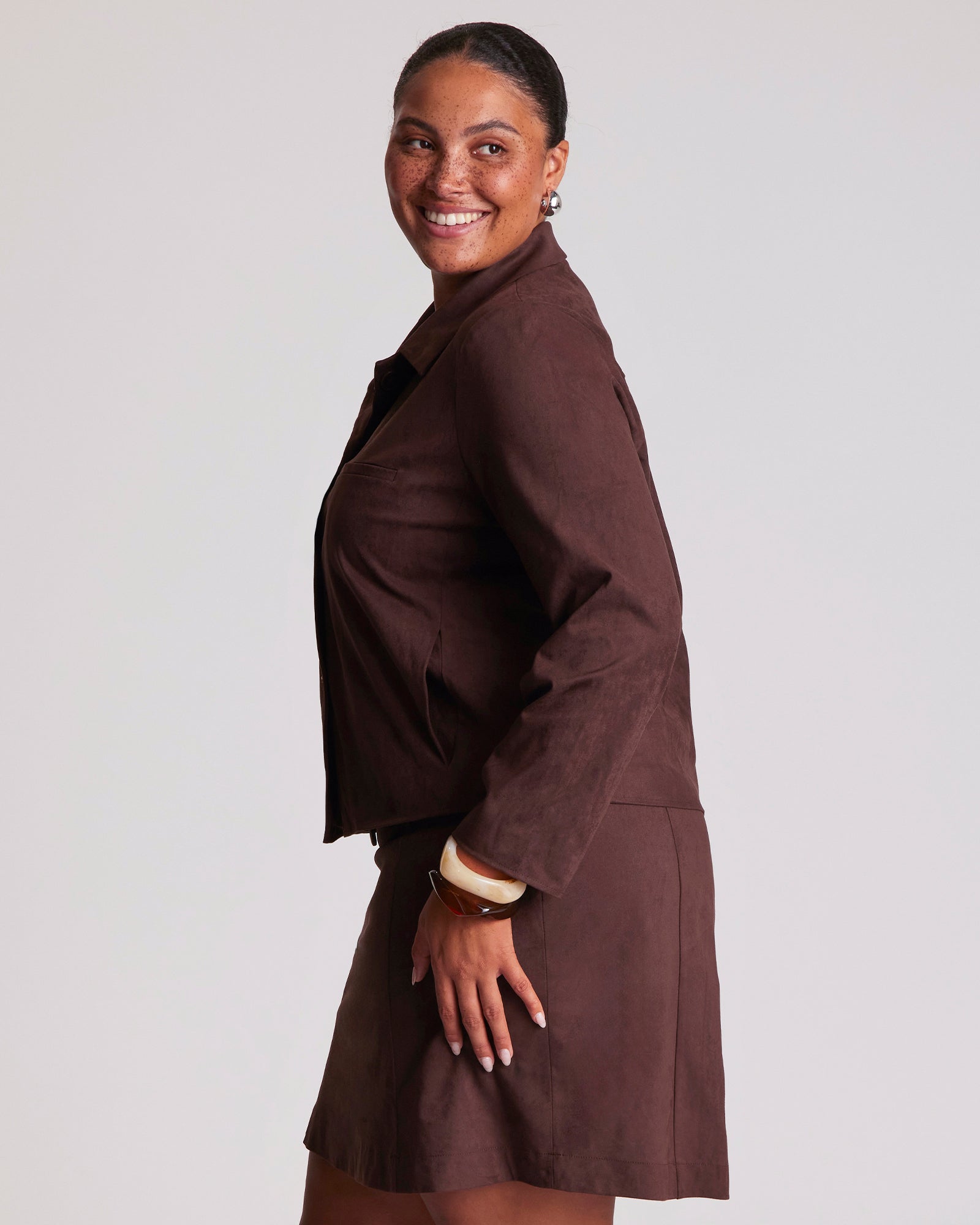 Woman wearing a brown coat against a plain background