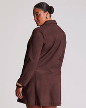 Person wearing a brown jacket and skirt set on a plain background