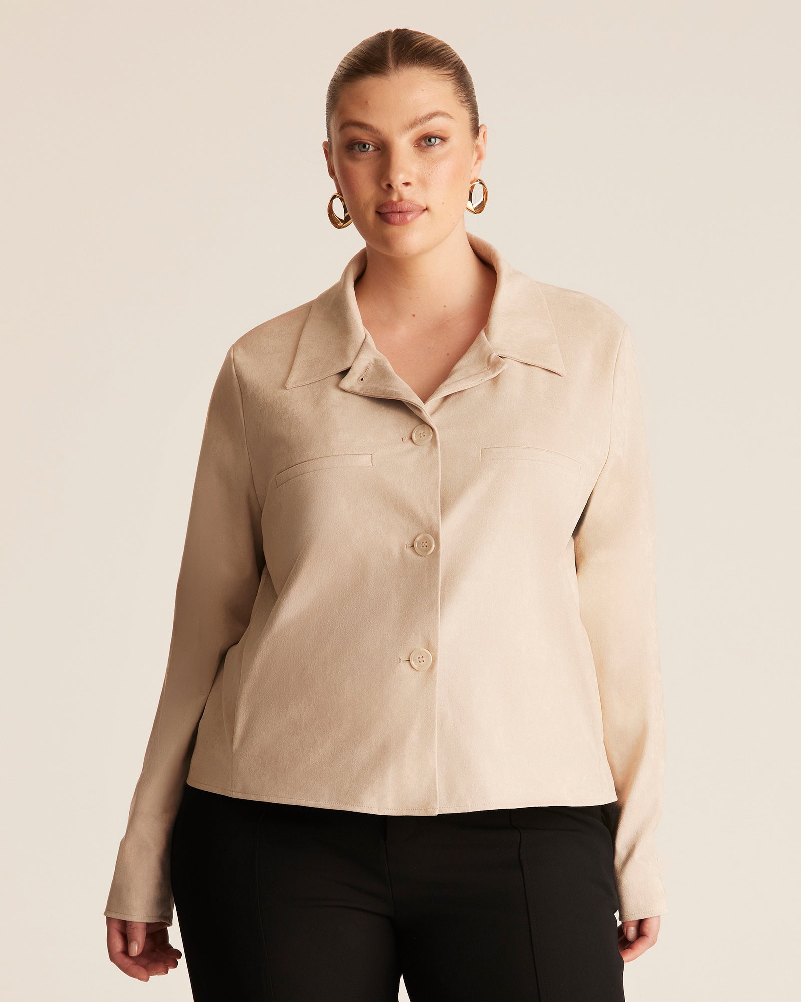 Woman wearing a beige jacket against a plain background
