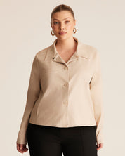 Woman wearing a beige jacket against a plain background