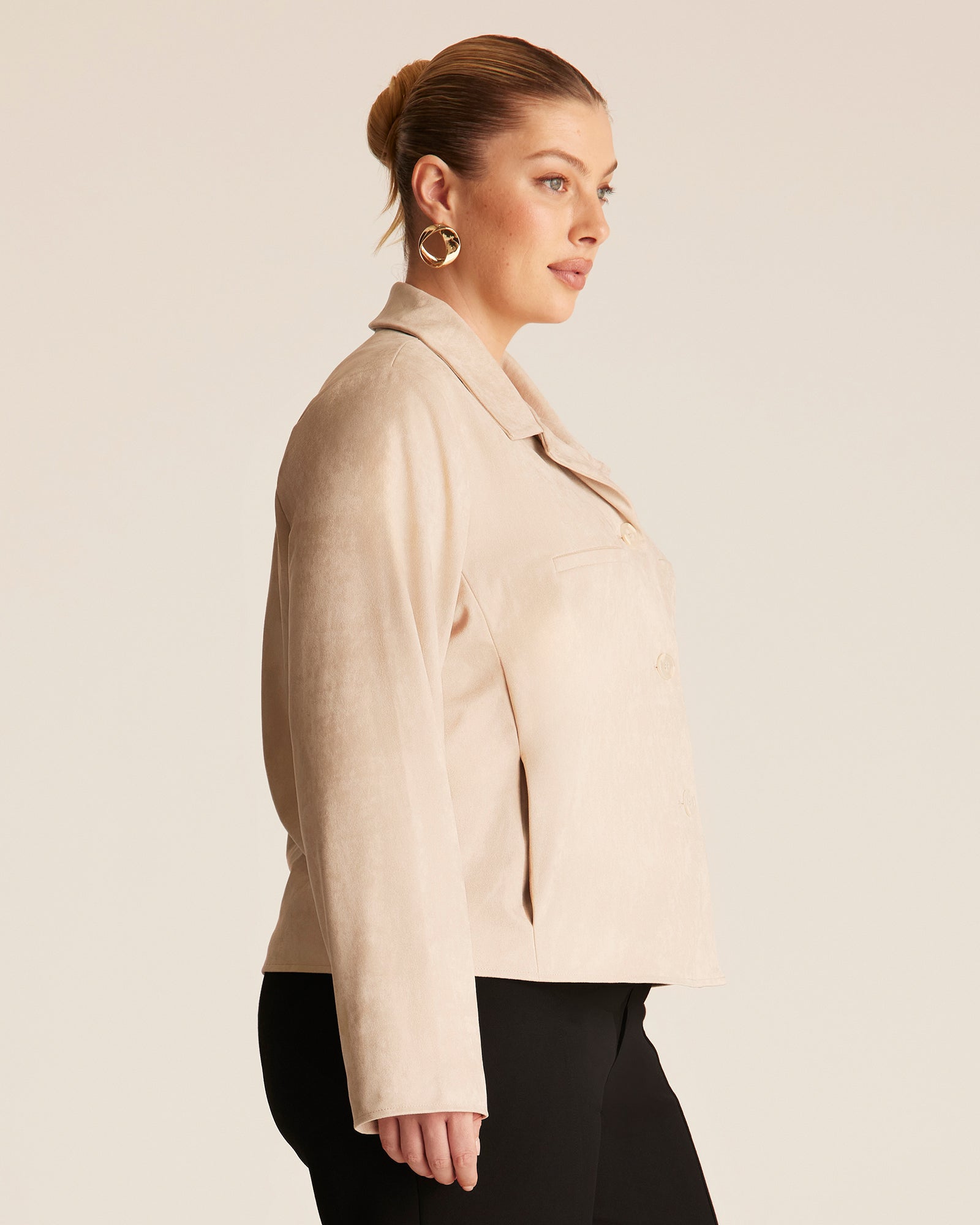 Woman wearing a beige coat against a plain background
