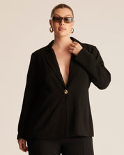 Woman wearing a black blazer with a beige background