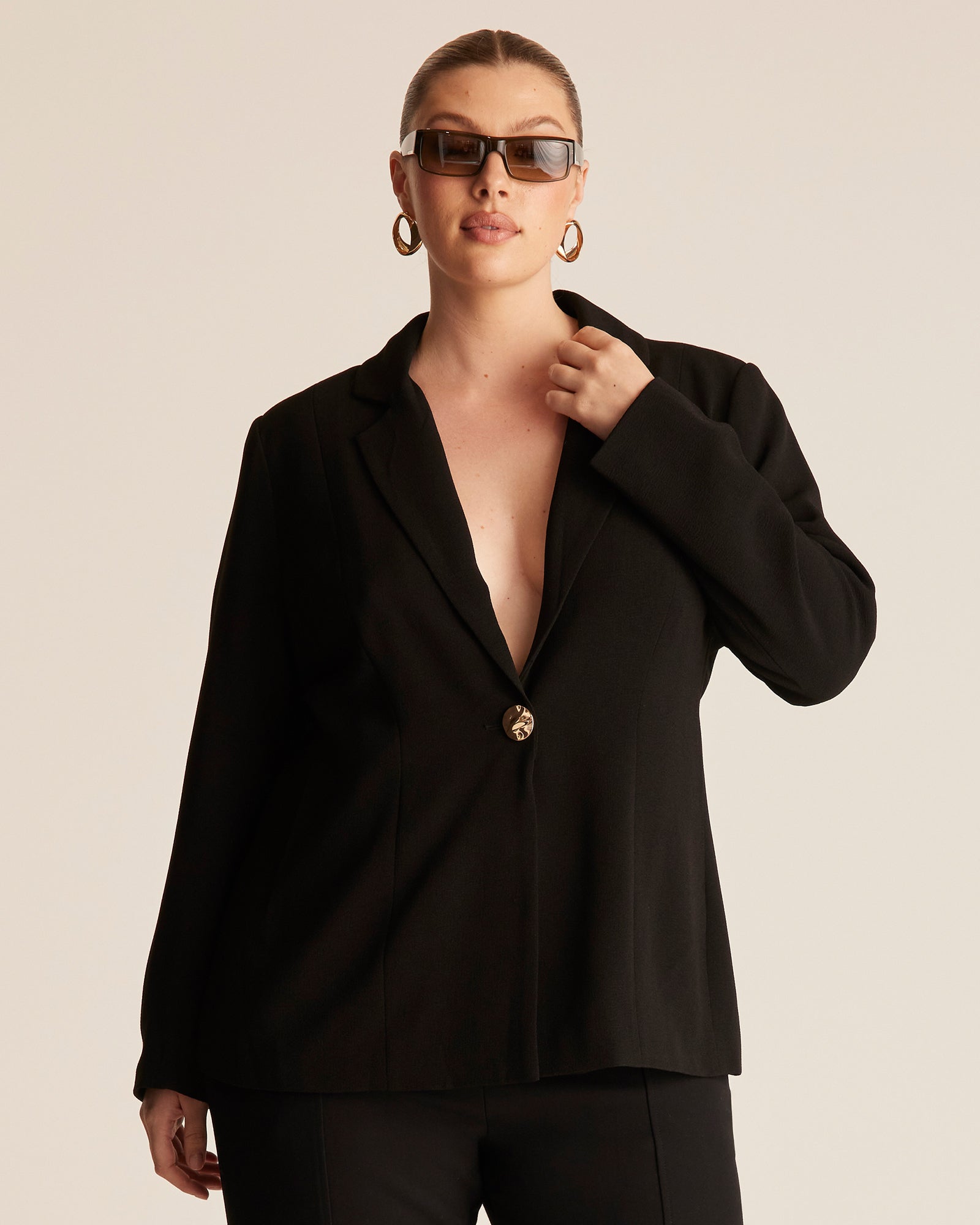 Woman wearing a black blazer with a beige background