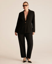 Woman wearing a black suit on a beige background