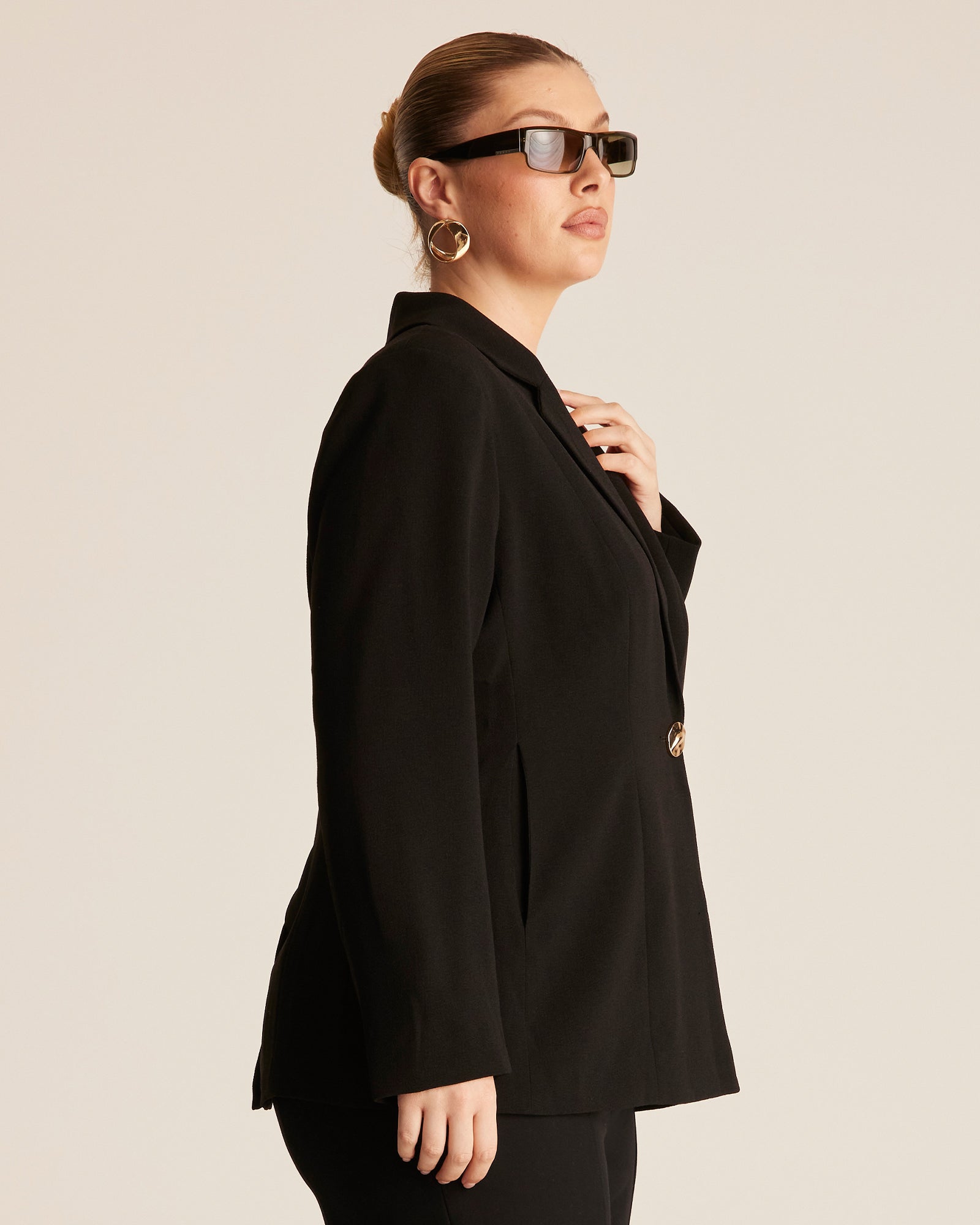 Person wearing a black blazer on a beige background
