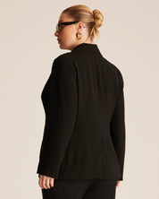 Person wearing a black blazer from behind on a beige background
