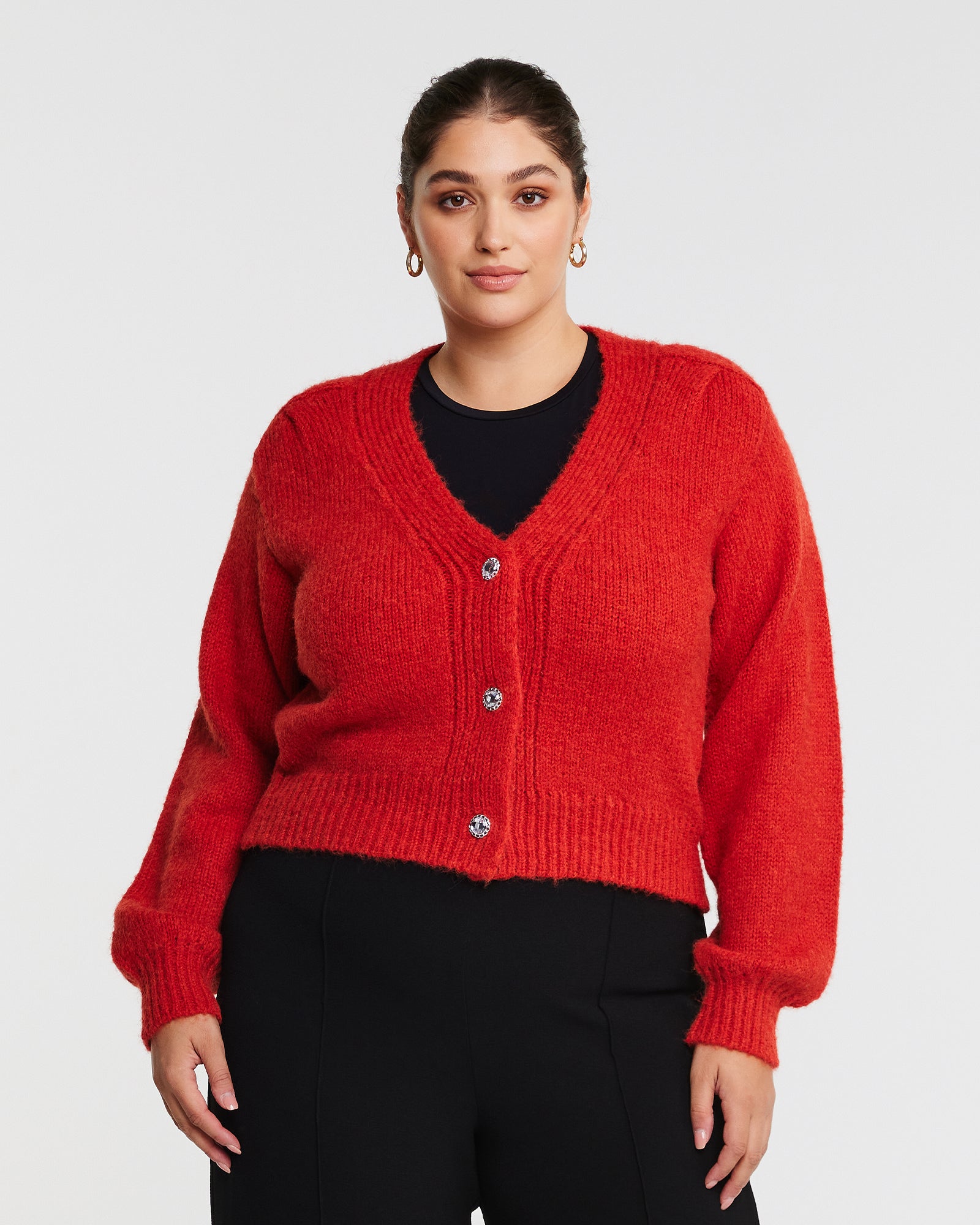 A model wearing a cozy embellished cardigan with silver buttons.