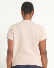 A person shown from the back wearing a short-sleeve knit top in a light cream or oatmeal color, photographed against a plain light background.