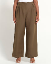 A model wearing a pair of wide-leg cropped pants in a solid taupe-brown color, paired with a white top and clear high-heeled sandals, photographed against a clean white studio background.