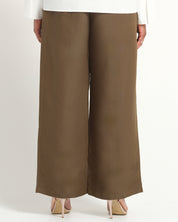 A person shown from the back wearing wide-leg cropped pants in a warm taupe-brown color, paired with a white top and beige heels, against a plain light background.