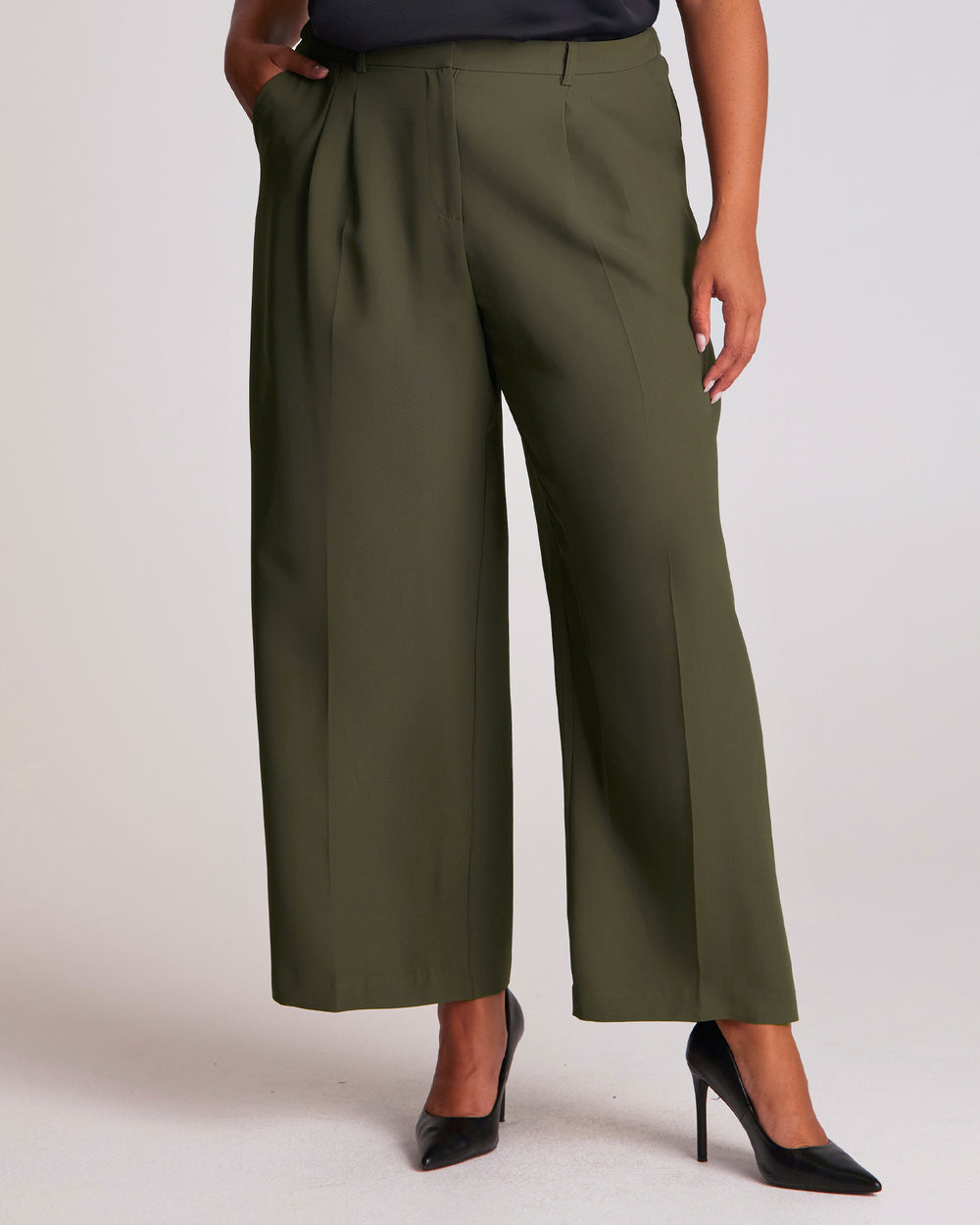 The Estelle Women's Olea Tailored Pant - Dark Green features a classic front fly opening, functional side pockets and back welt pockets for a clean, tailored appearance. Elasticated side waist panels provide added comfort while maintaining a polished silhouette, and the lined pocket bags create a considered finish. The wide-leg cut offers versatile styling options, making these women's wide-leg trousers an effortless choice for both professional and casual outfits.