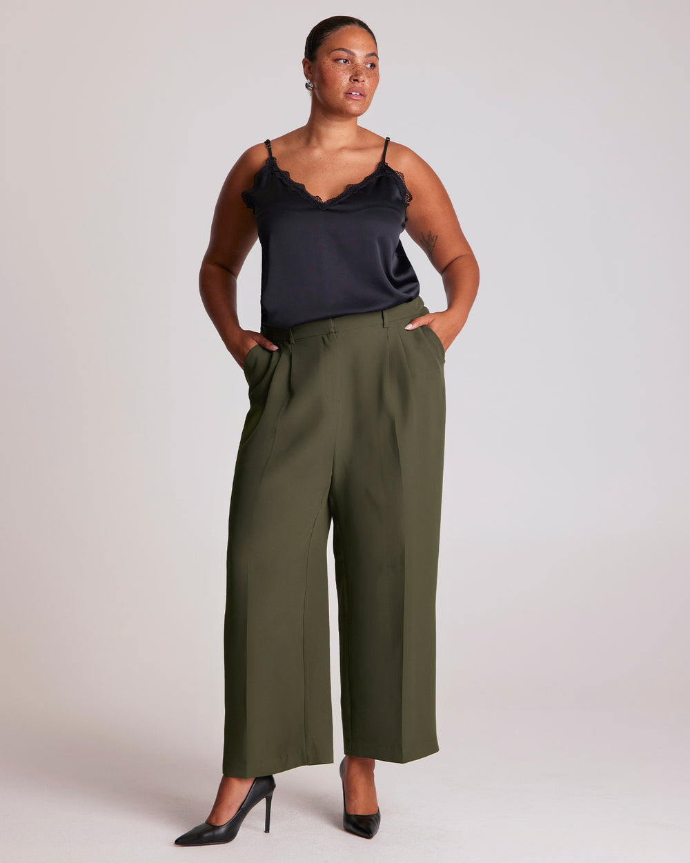 The Estelle Women's Olea Tailored Pant - Dark Green features a classic front fly opening, functional side pockets and back welt pockets for a clean, tailored appearance. Elasticated side waist panels provide added comfort while maintaining a polished silhouette, and the lined pocket bags create a considered finish. The wide-leg cut offers versatile styling options, making these women's wide-leg trousers an effortless choice for both professional and casual outfits.