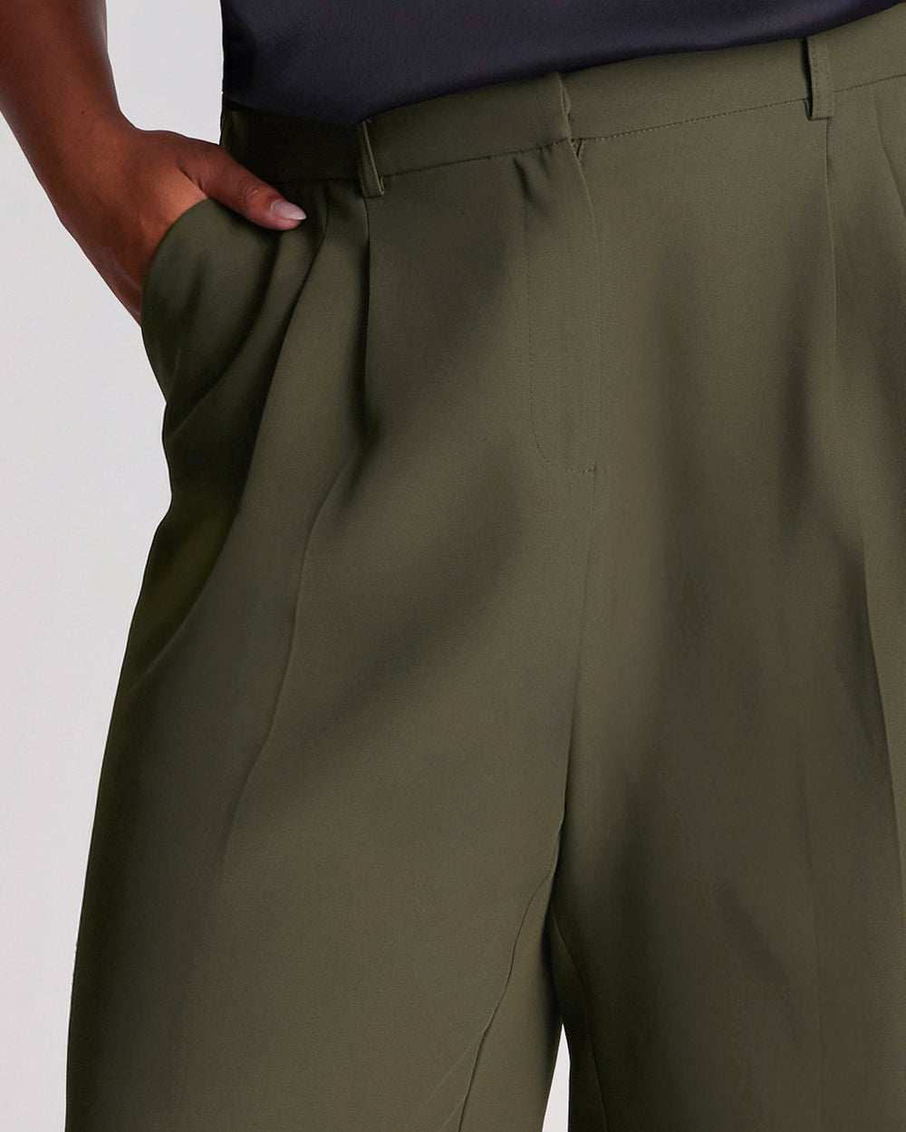 The Estelle Women's Olea Tailored Pant - Dark Green features a classic front fly opening, functional side pockets and back welt pockets for a clean, tailored appearance. Elasticated side waist panels provide added comfort while maintaining a polished silhouette, and the lined pocket bags create a considered finish. The wide-leg cut offers versatile styling options, making these women's wide-leg trousers an effortless choice for both professional and casual outfits.