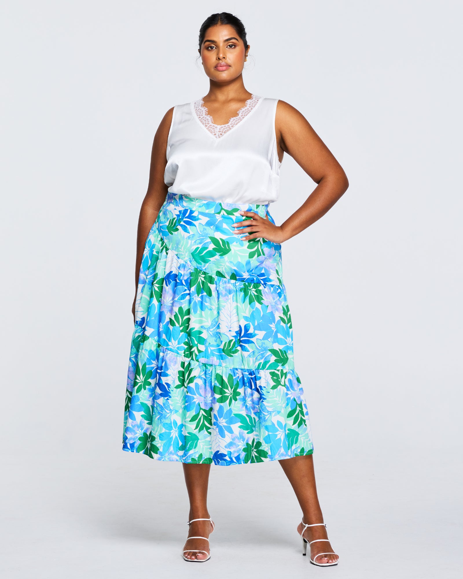 A plus size woman wearing the Estelle Travola Tiered Skirt in a blue and green floral midi skirt.